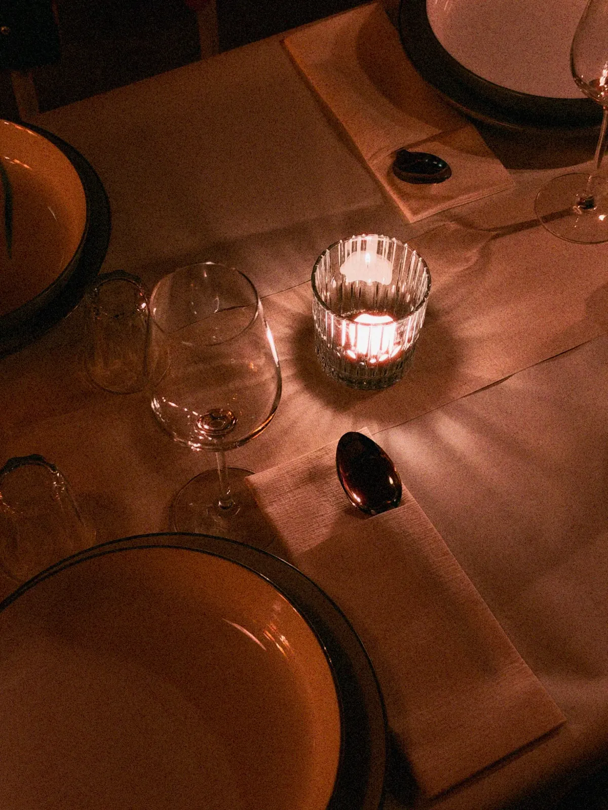 Kerzen, Gläser, Besteck und Teller auf einem Dinnertisch