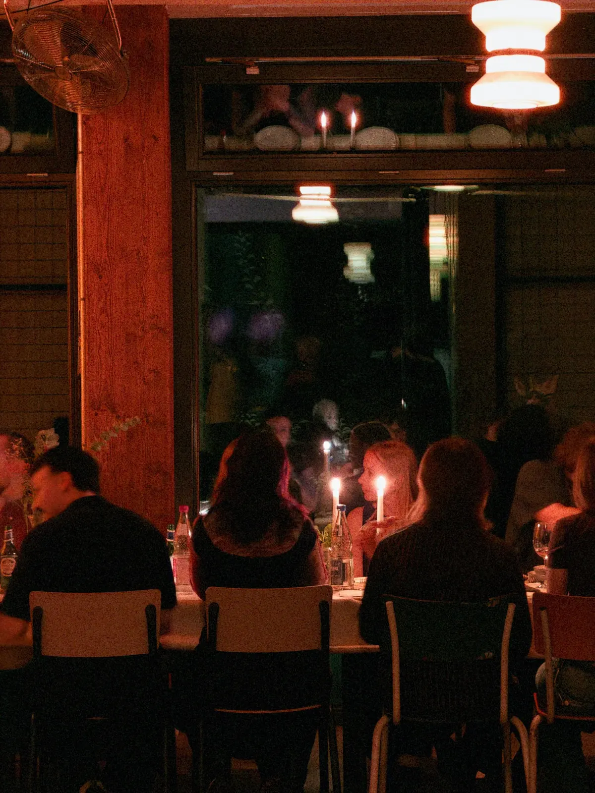 Gäste bei einem gemeinsamen Dinner mit Kerzenschein am Fenster