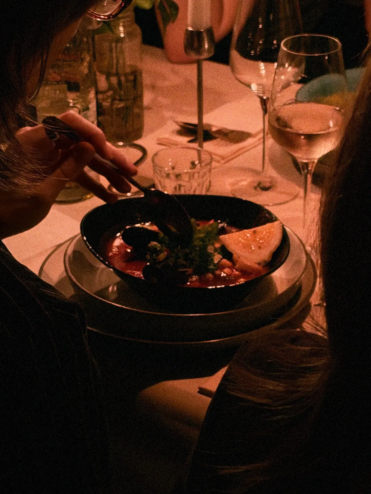 Ein Gast isst Suppe bei Wein und Kerzenschein