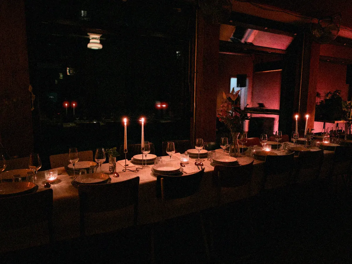A long table set with plates, glasses and candles for dinner